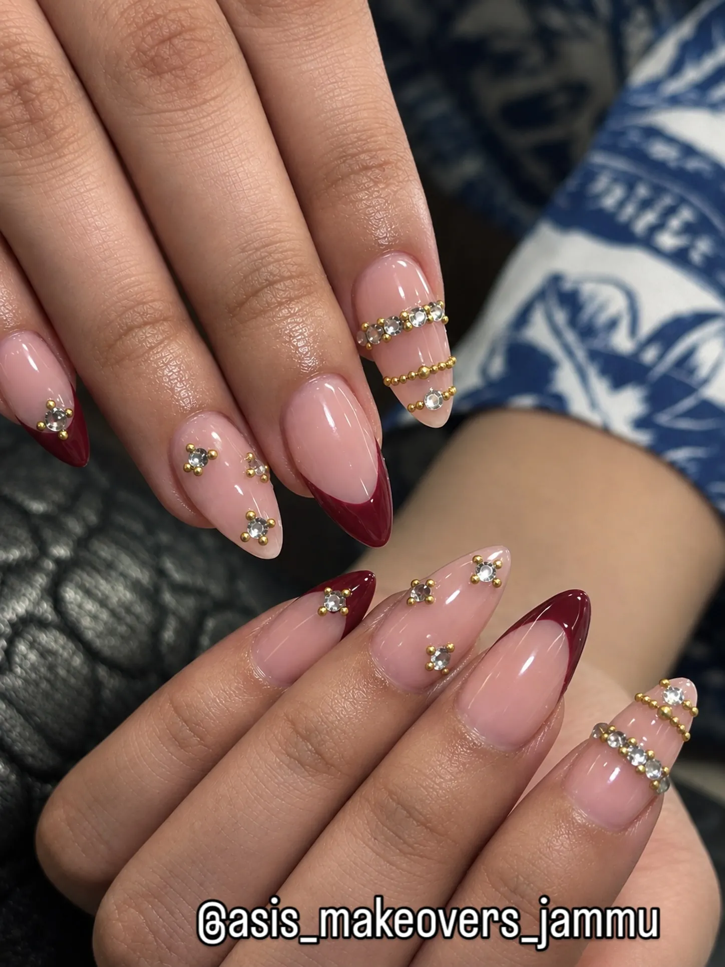 Burgundy French nails with small gem clusters and gold band accents