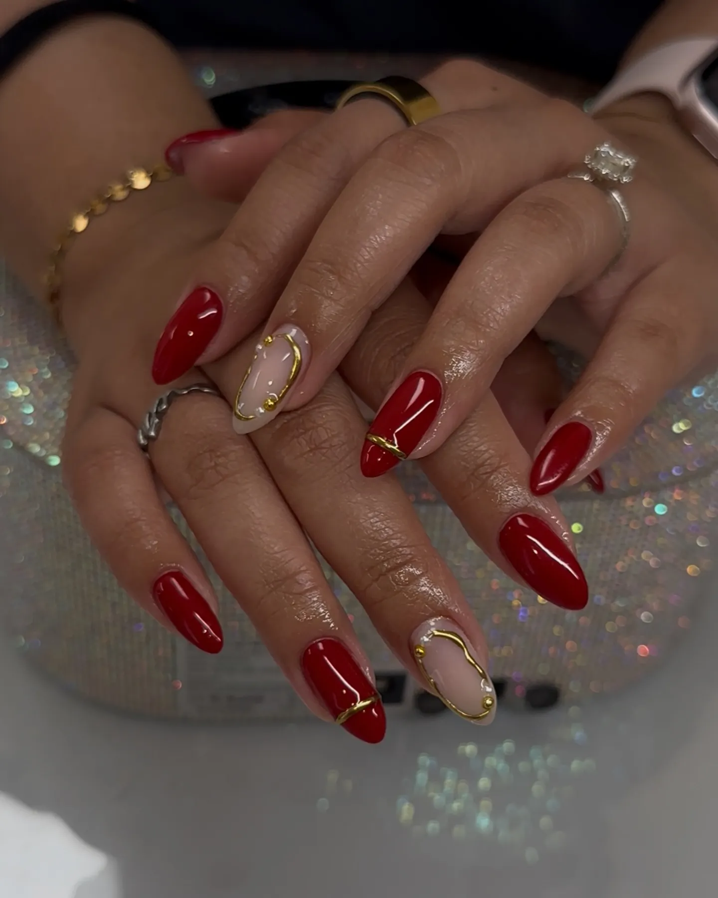 Solid red almond nails with gold bands and pale pink framed accents