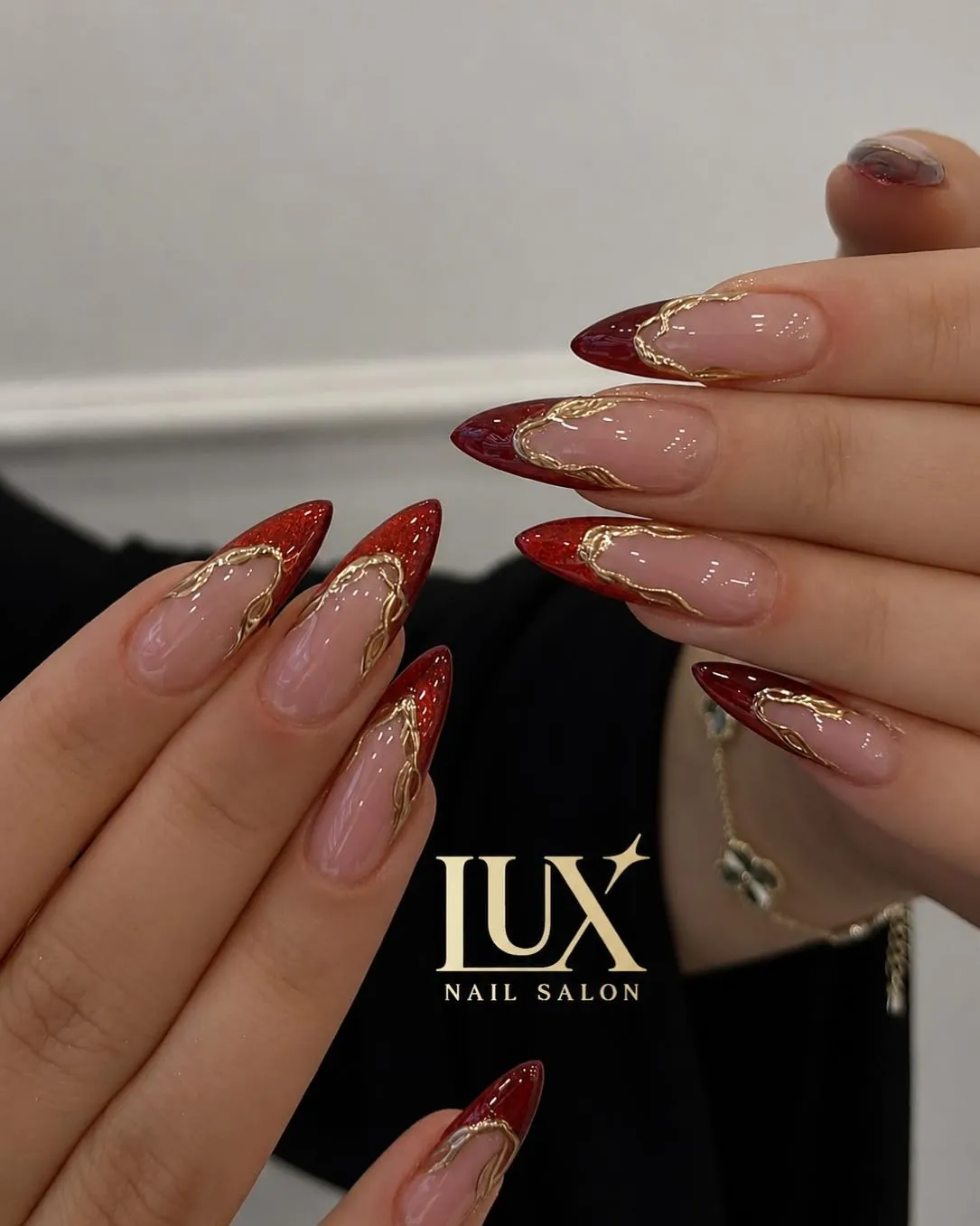 Long pointed red French nails with fine curved gold outlines