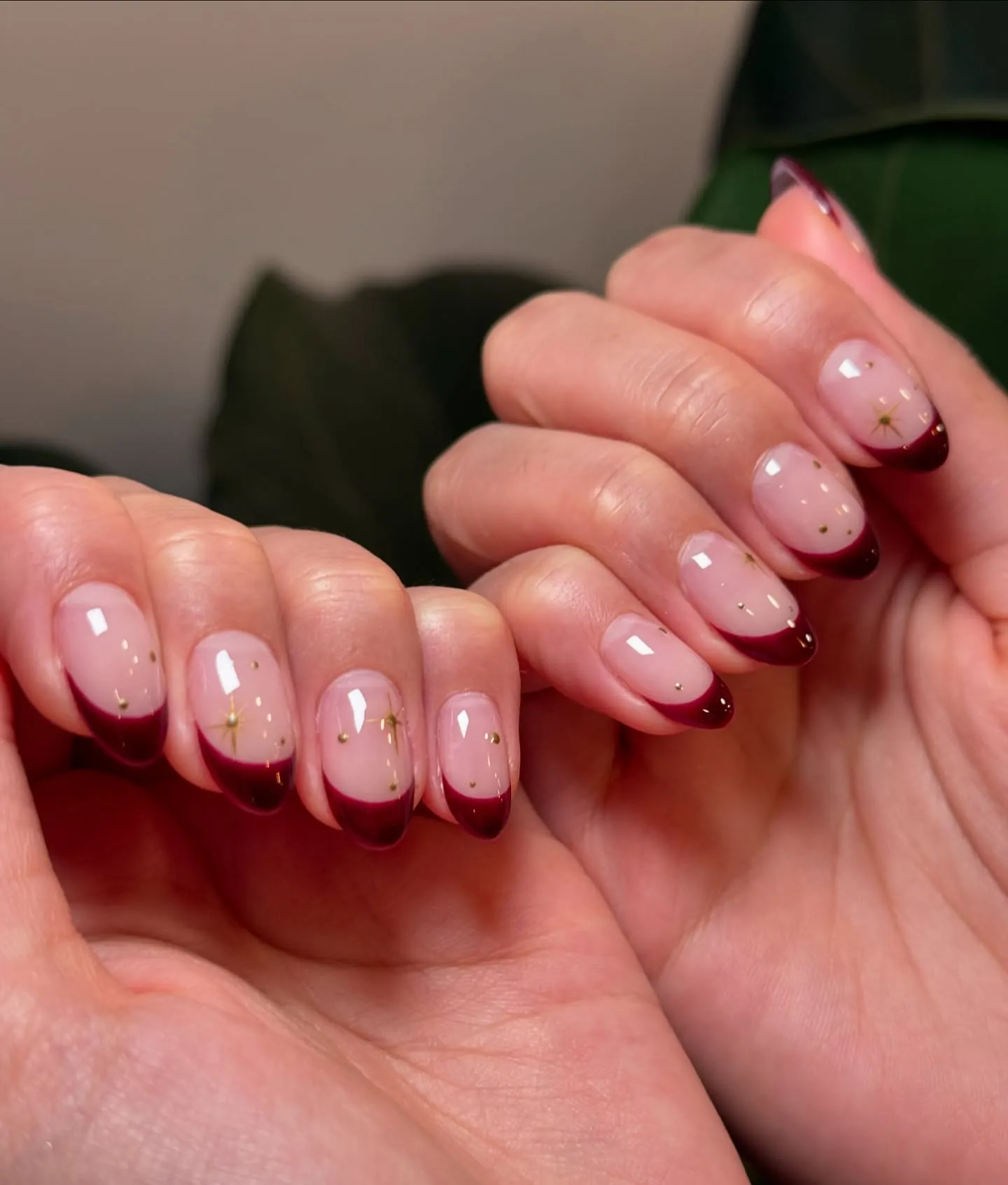 Short pink nails with burgundy French tips and tiny gold flecks