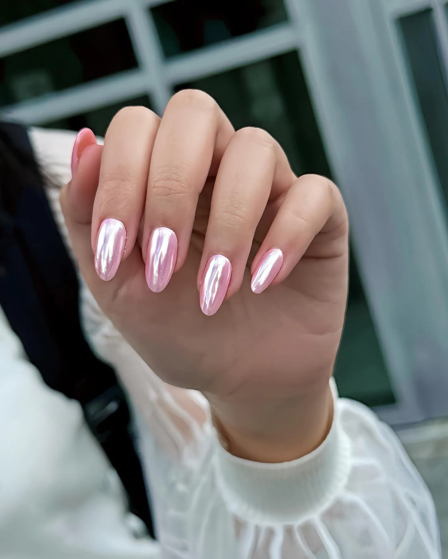 Pink almond chrome nails with bright vertical reflections