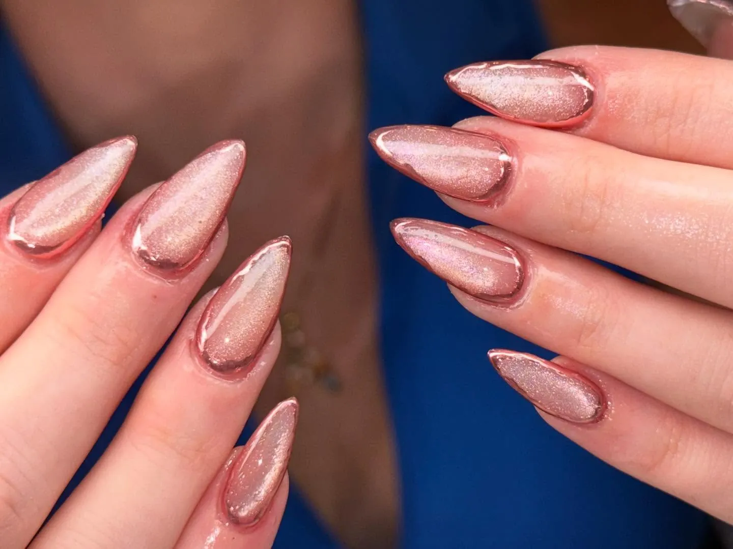 Pointed pink shimmer nails bordered with darker rose metallic outlines