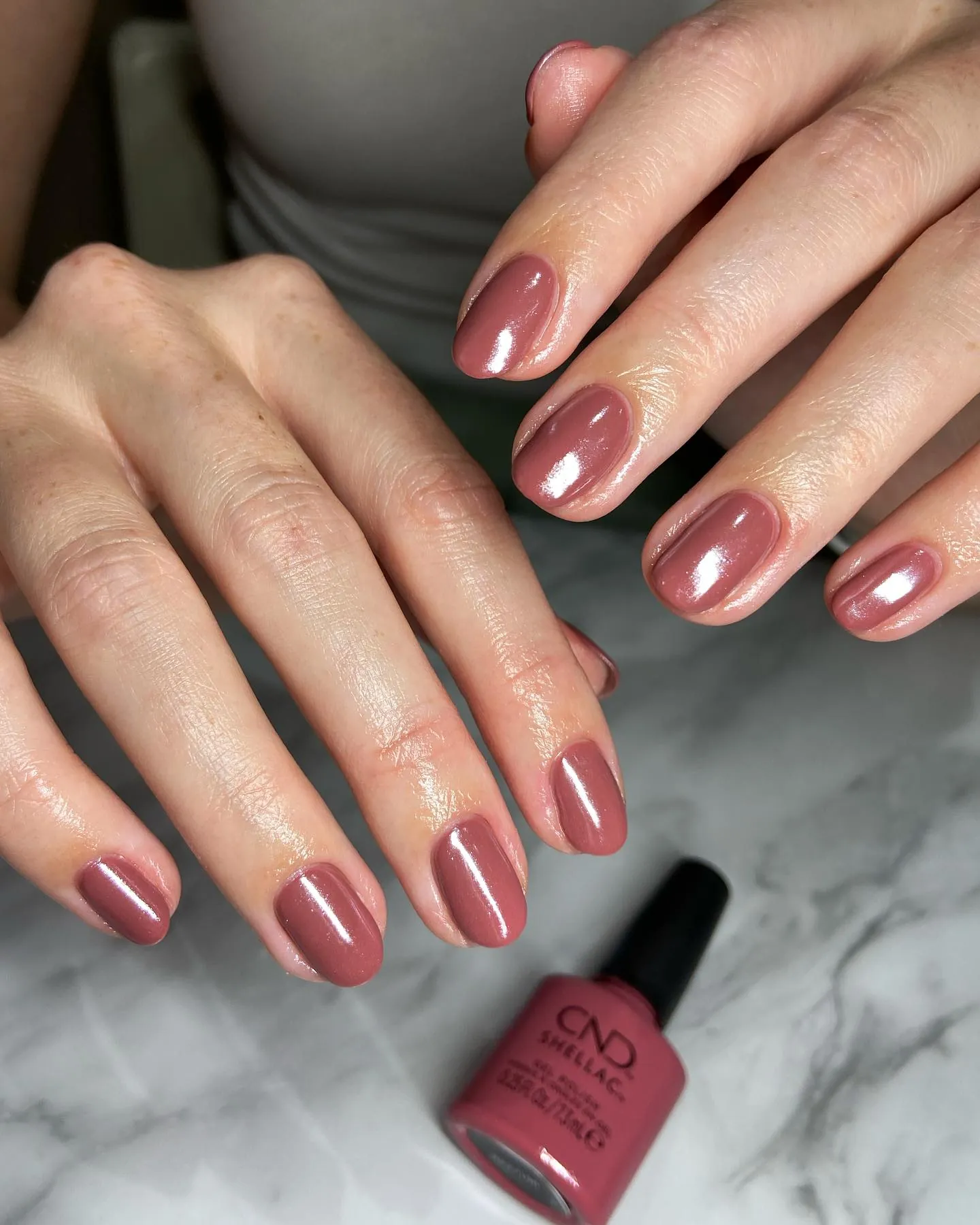 Short rounded nails with a warm rosy reflective finish