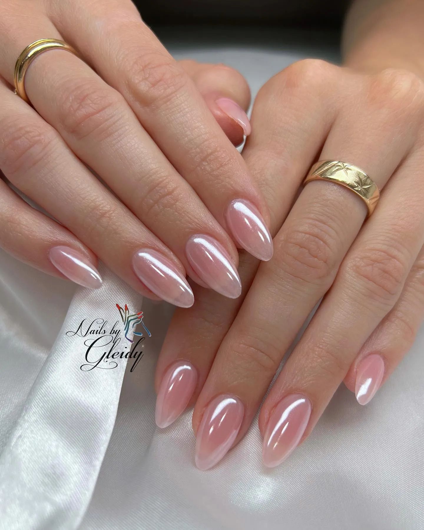 Sheer pale pink almond nails with a soft reflective sheen