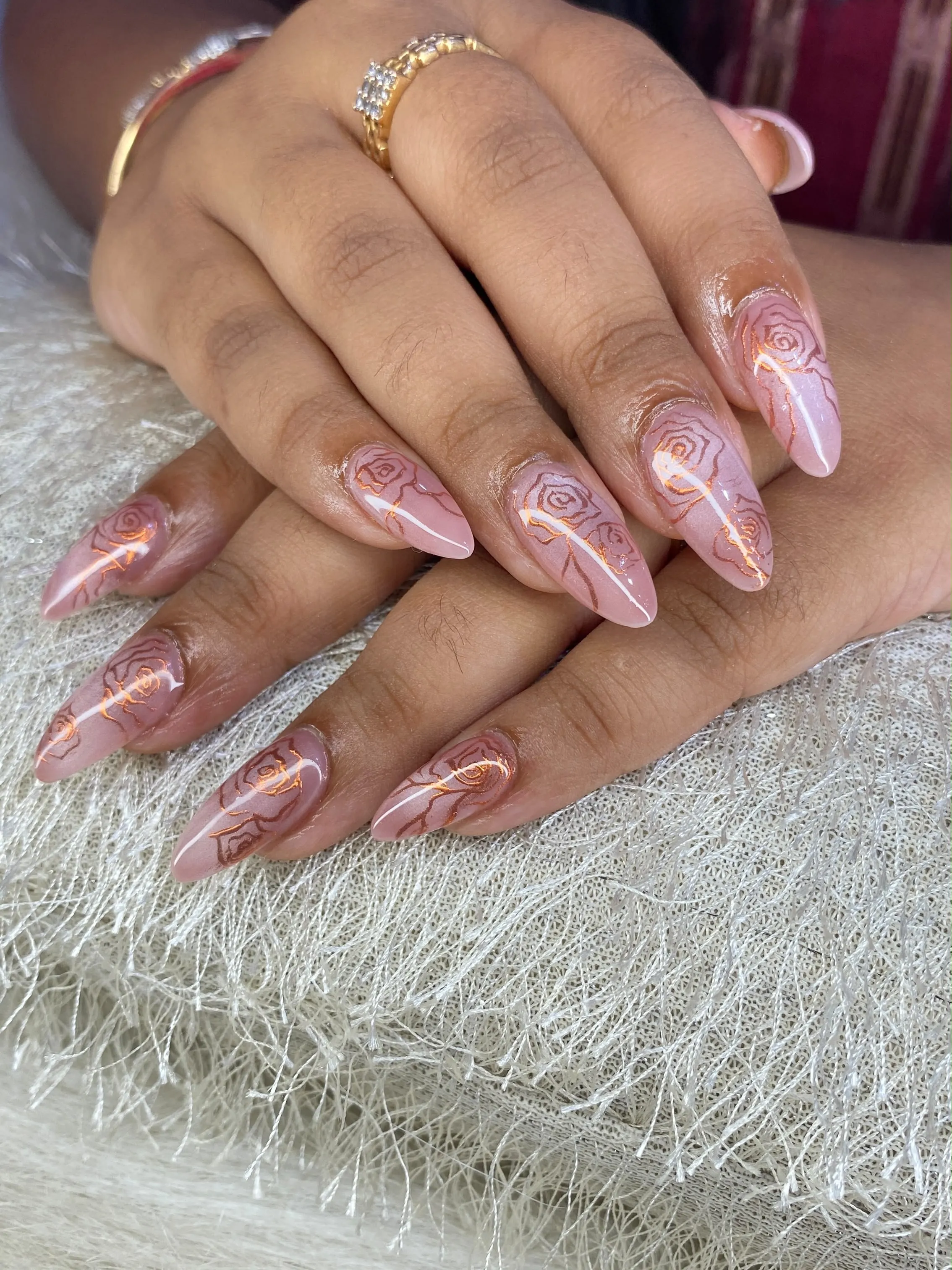 Pale pink almond nails with fine metallic rose flower outlines