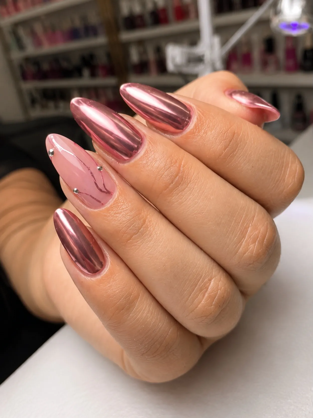Rose metallic almond nails paired with a pink decorative accent