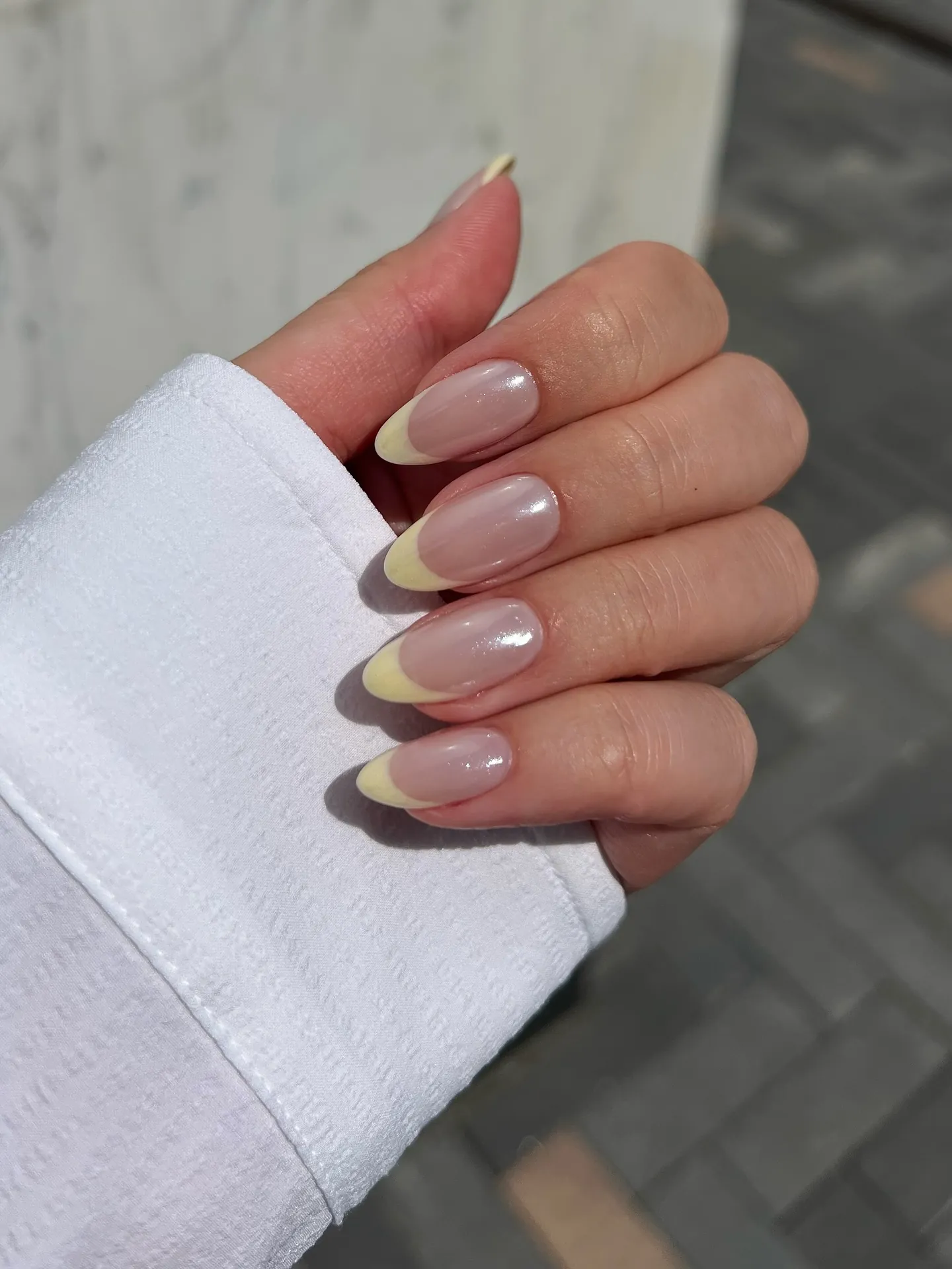 Rounded pink nails with pale yellow tips and a soft reflective sheen