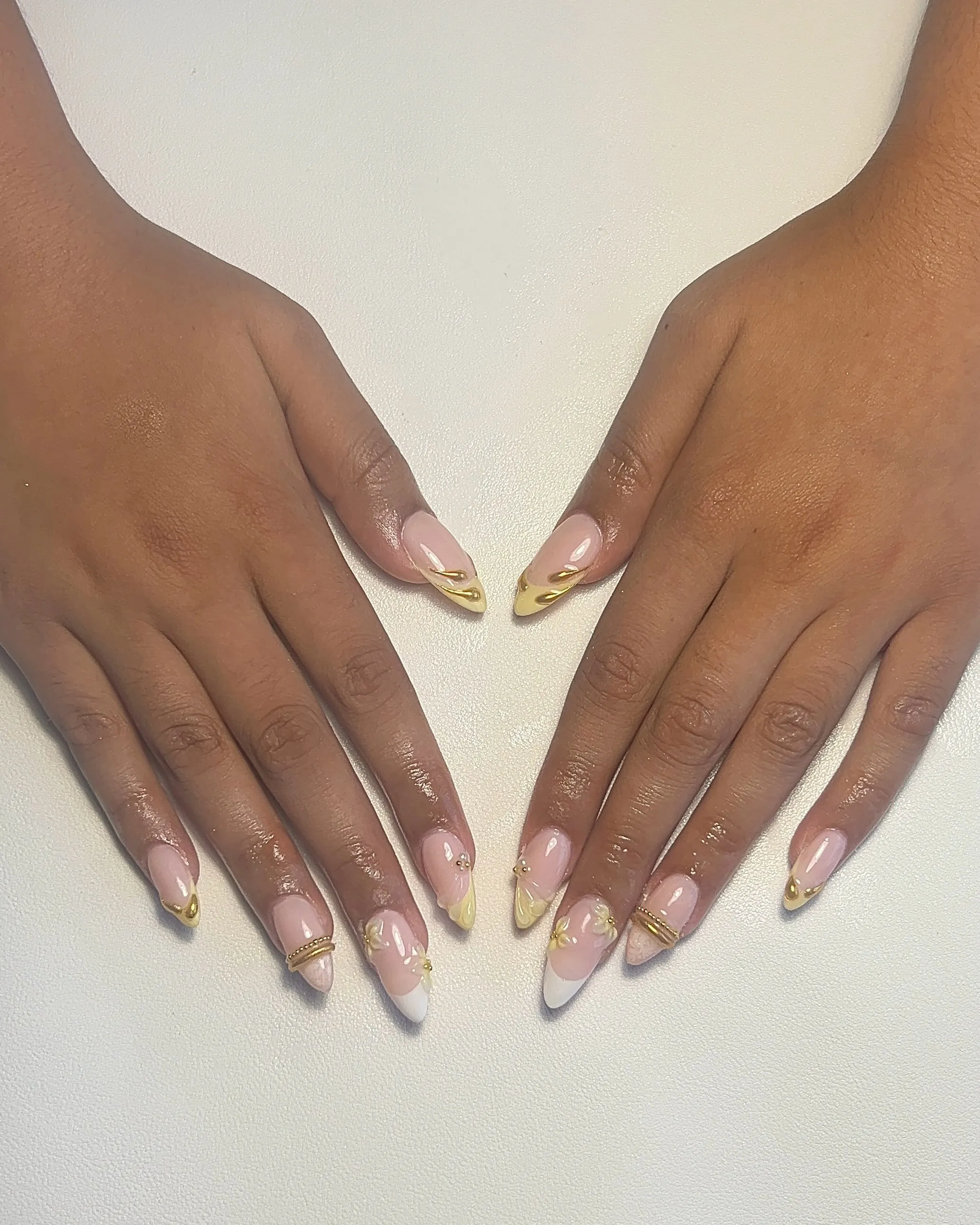 Mixed yellow and white French nails with gold accents and small flowers