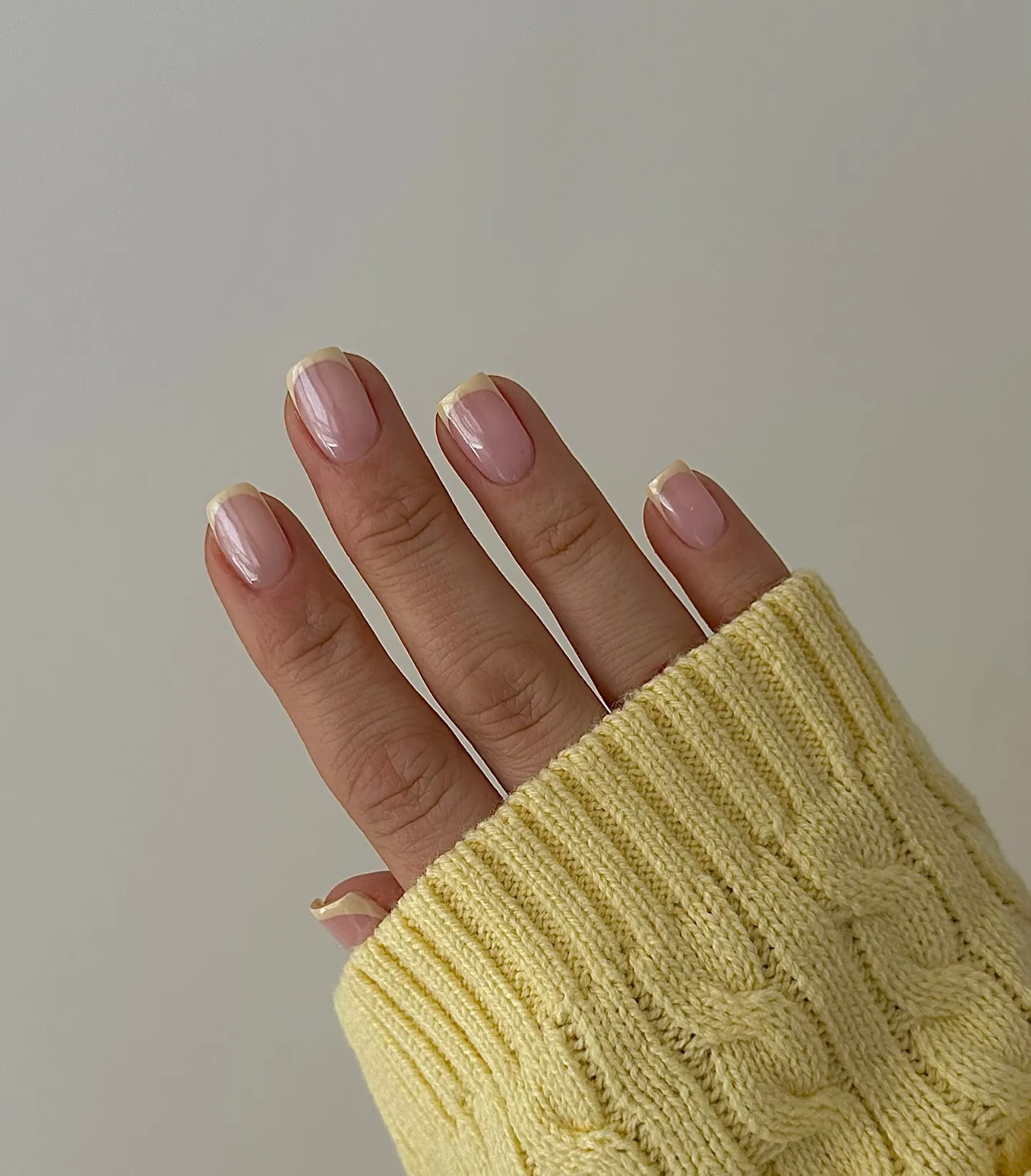 Short pink nails with a pearly sheen and fine pale yellow tips