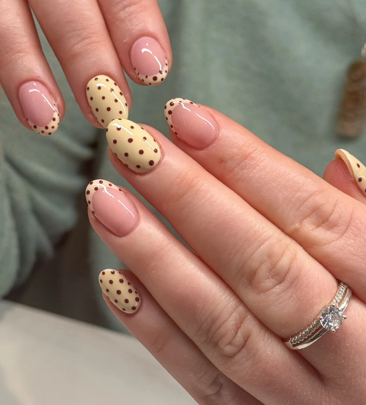Short rounded nails mixing dotted pale yellow color and pink French accents