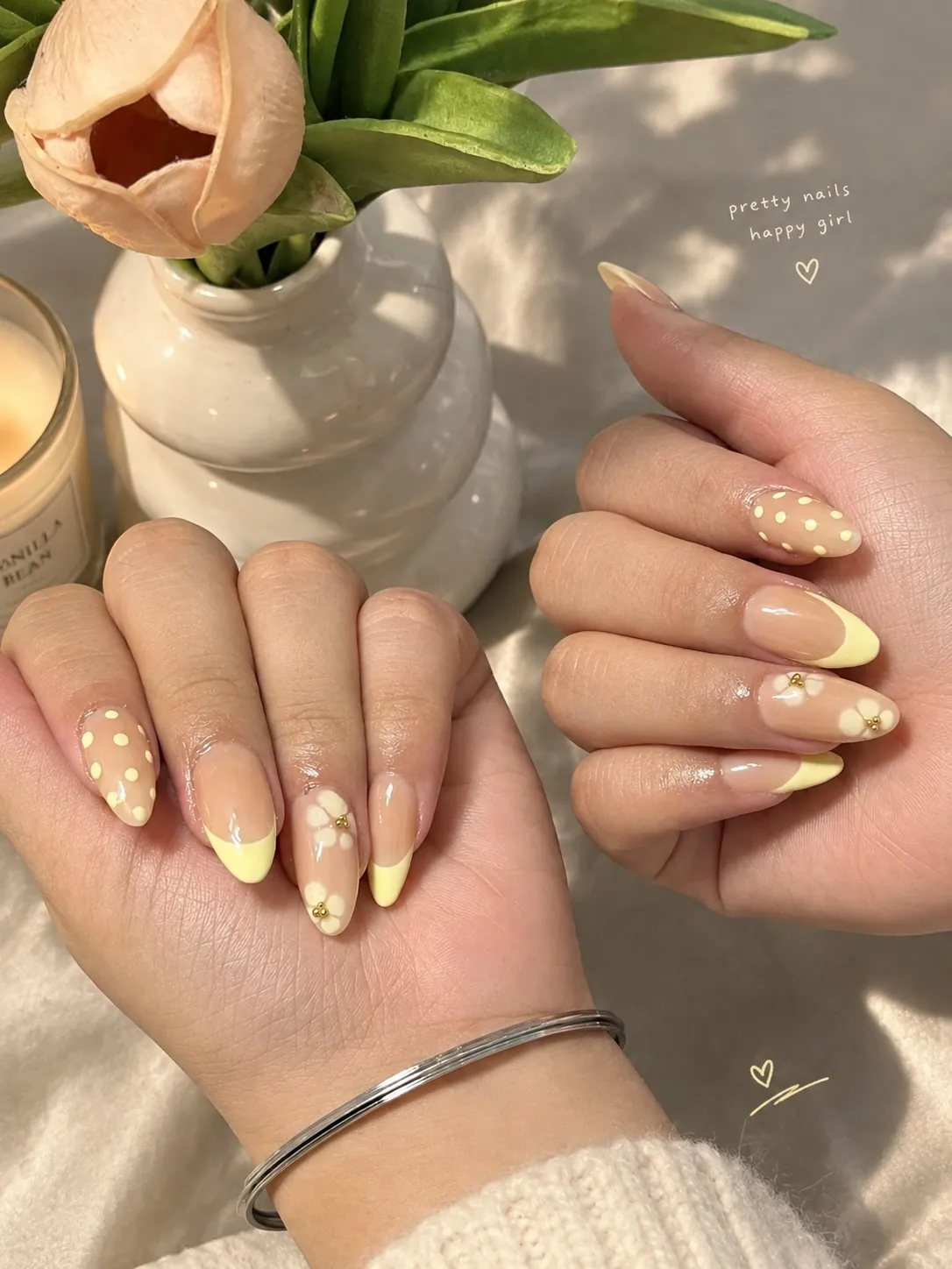 Almond nails mixing pale yellow French tips with yellow flowers and white dots