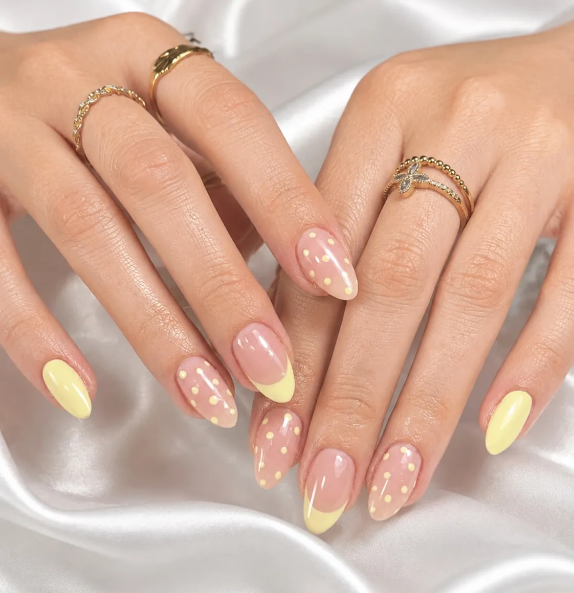 Almond nails with yellow French tips, solid yellow accents and small white flowers