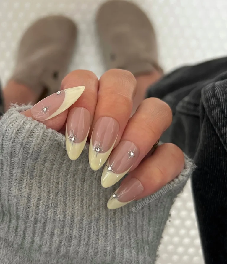 Almond nails with pale yellow French tips, sheer nude bases and tiny white dot accents.