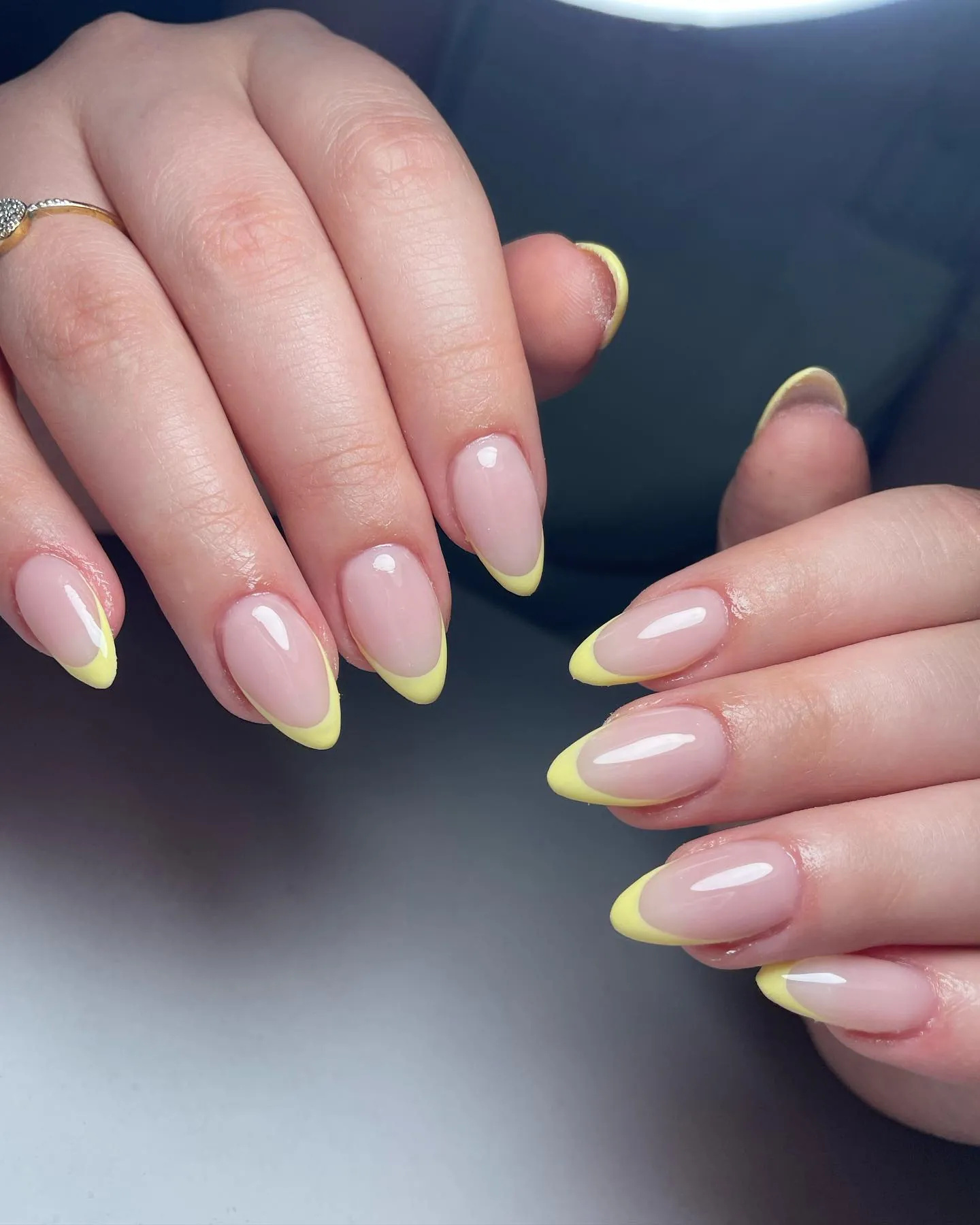 Glossy pink almond nails with slim bright yellow French tips