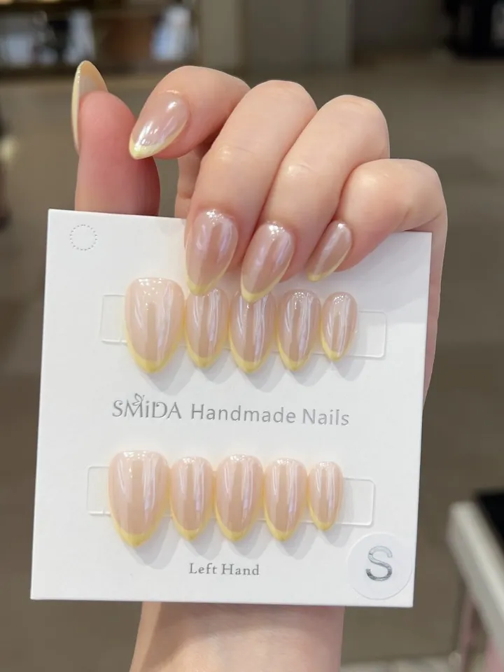 Sheer pearly almond nails with fine yellow French tips