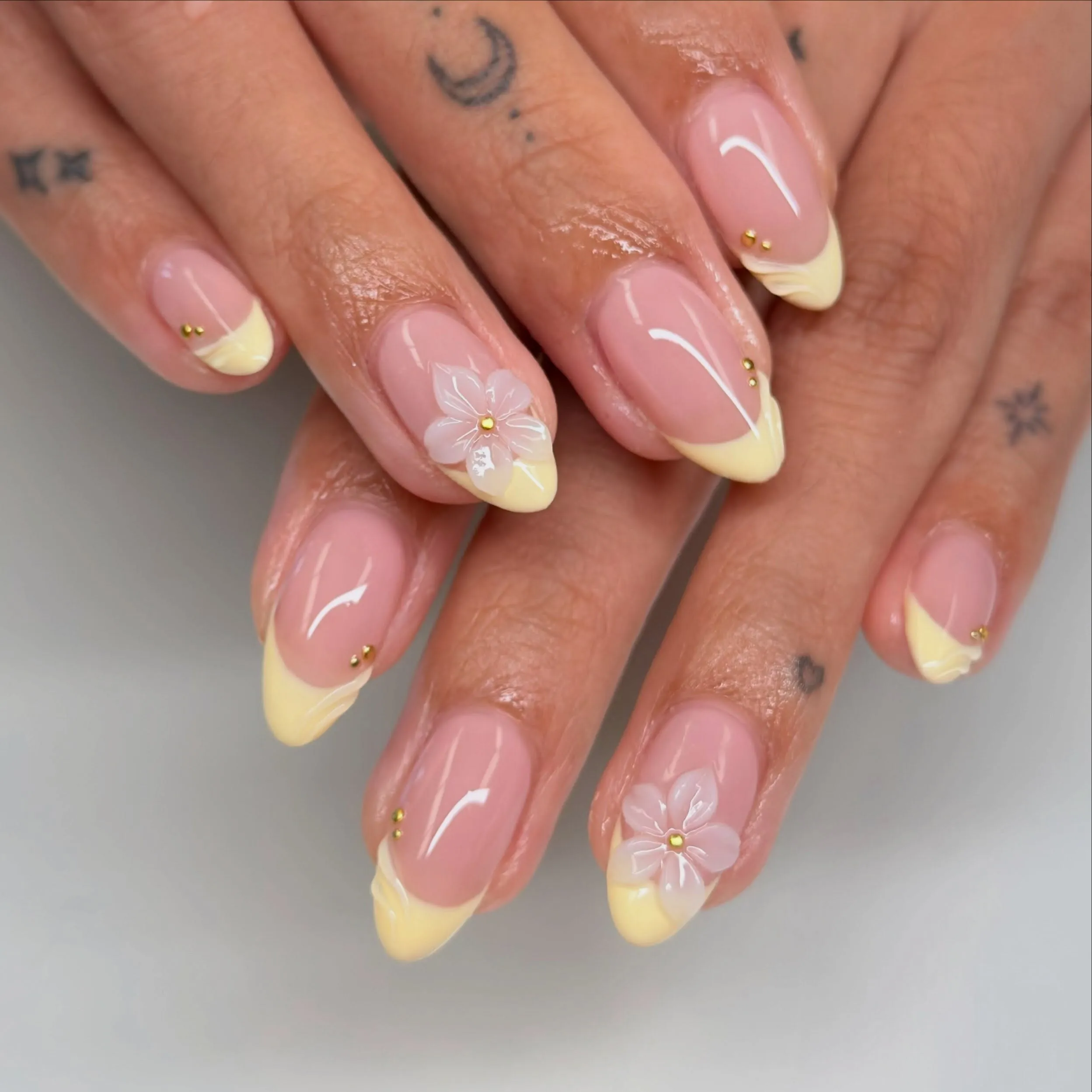Pink almond nails with yellow French tips and white flowers
